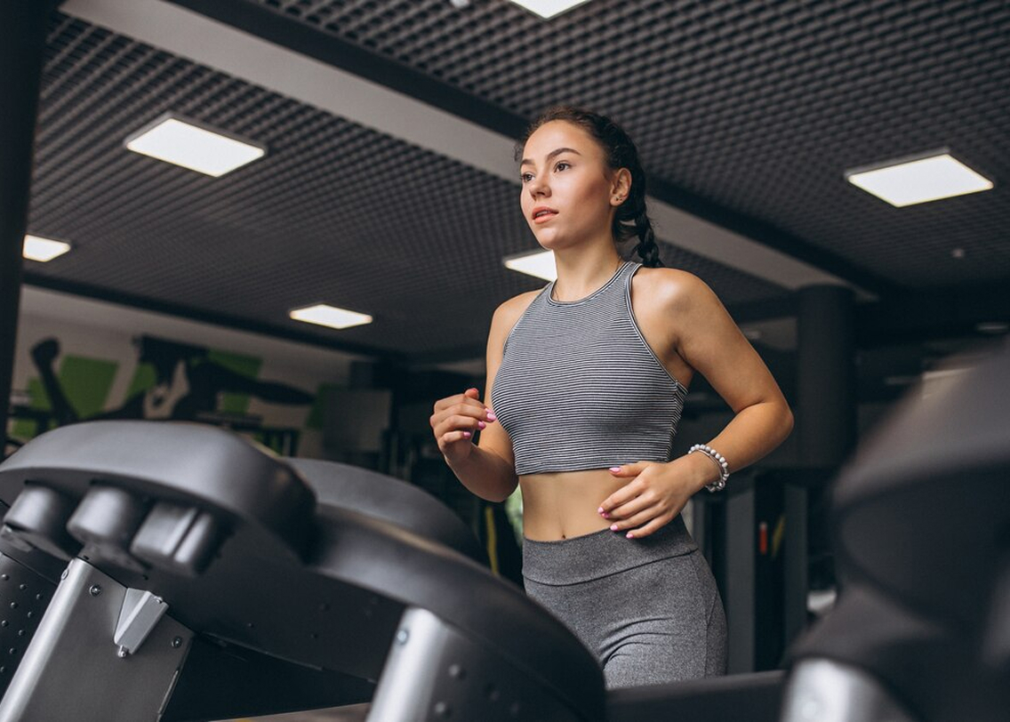 Девушка бежит по беговой дорожке в спортзале